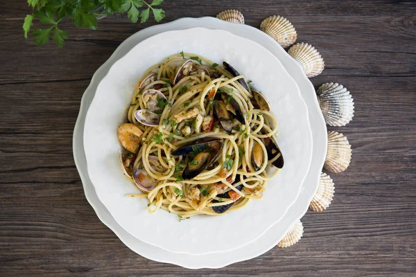 Spaghetti z owocami morza w biały ceramiczny talerz na drewniane backgrou — Zdjęcie stockowe