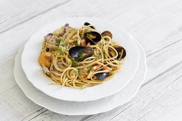 Spaghetti met zeevruchten in witte keramische plaat op houten CHTERGRO — Stockfoto