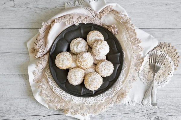 Coconut biscuits with icing sugar over pewter plate