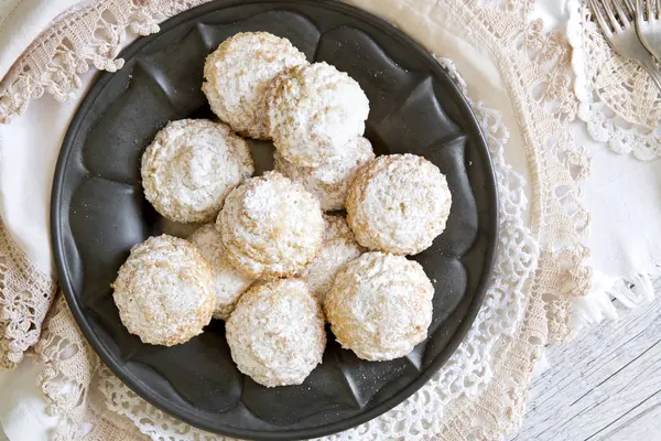 Coconut biscuits with icing sugar over pewter plate