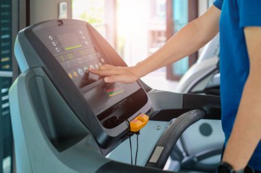 Şehirdeki insanların yaşam tarzları ve spor aktiviteleri konseptindeki spor salonundaki koşu bandında koşan sporcuya yakın çekim