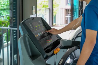 Şehirdeki insanların yaşam tarzları ve spor aktiviteleri konseptindeki spor salonundaki koşu bandında koşan sporcuya yakın çekim