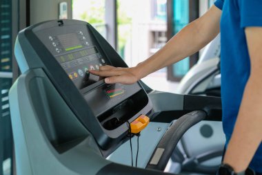 Şehirdeki insanların yaşam tarzları ve spor aktiviteleri konseptindeki spor salonundaki koşu bandında koşan sporcuya yakın çekim
