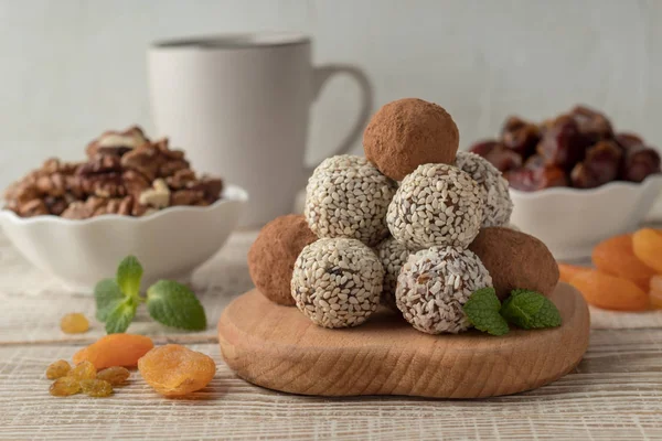 Energy bites with cocoa powder, sesame seeds and coconut flakes on white wooden table