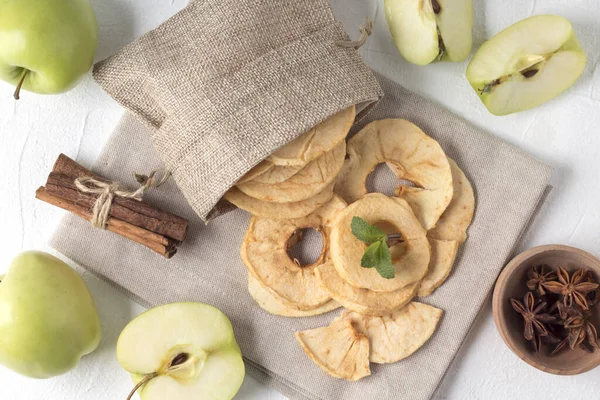 Flat lay composition with apple chips in small sack on white table. Natural vegan snack. Yummy paleo recipe