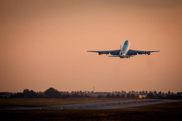 Огромный грузовой самолет взлетает на закате
