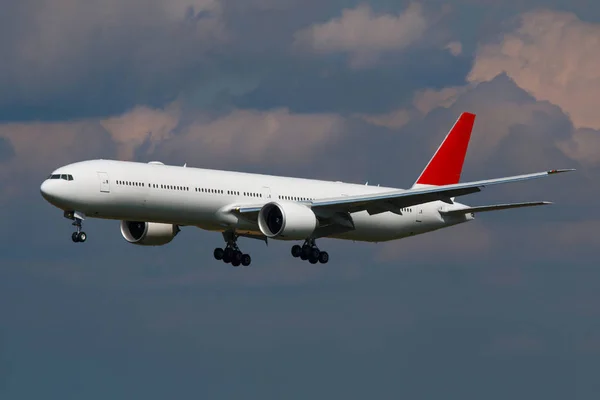 Bílá obrovské letadlo s červeným ocáskem se blíží k přistání na letišti — Stock fotografie