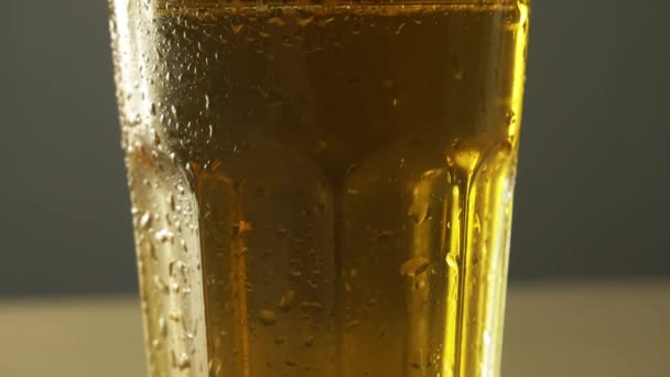 Bardak dolu sarı el işi bira yakın çekim tavası ve bir damla yoğuşma soğuk içecek 4K — Stok video