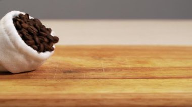 Kavrulmuş kahveden beyaz torba düştü. Tahıl yavaş yavaş, yakın çekim. Arabika masası döküldü.