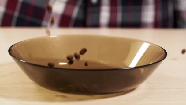 Man gooien vallen gebrande koffieboon op plaat slowmotion closeup container Arabica — Stockvideo