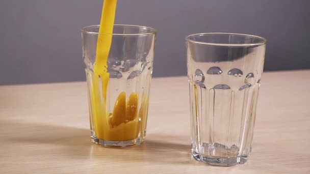 Dos vasos vacíos llenos refrescan el zumo de naranja slow motion fondo blanco de cerca — Vídeos de Stock