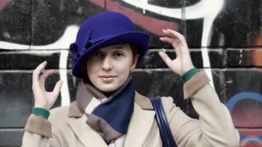 Büyüleyici kişi mavi şapkalı gülüşünü kaldırıyor. Arka plandaki sanat eserlerine yakından bakıyor..