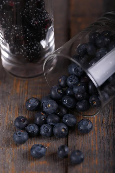 Gelas kaca dengan blueberry dan blackberry pada latar belakang kayu — Stok Foto