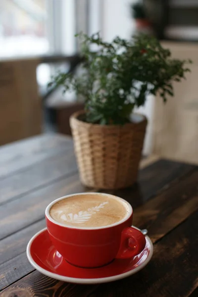 Una taza grande de café rojo en una mesa de madera . — Foto de Stock