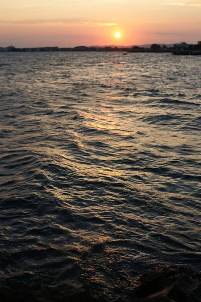 港の海水に太陽光が反射して海岸のロマンチックな夕日を背景に — ストック写真