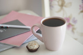růžový šálek čaje s cukrovinkami na bílém stole pozadí