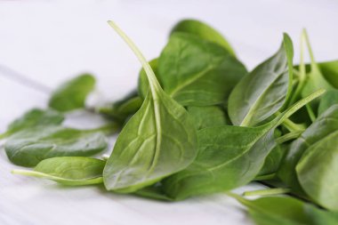 Green leaves of fresh baby spinach on white wooden table background