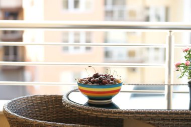 Olgun ve taze kirazlar siyah masa arka planında renkli kâsede.