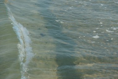 Deniz kıyısında dalgalanan küçük dalgalarla deniz suyu 