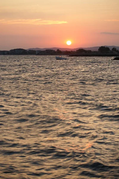 港の海水に太陽光が反射して海岸のロマンチックな夕日を背景に — ストック写真