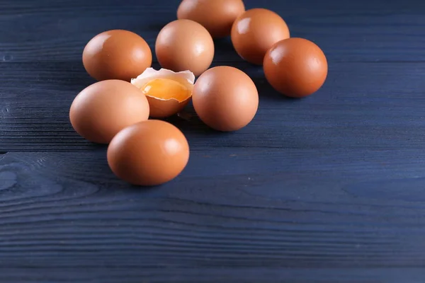 chicken eggs with one cracked egg on blue wooden background
