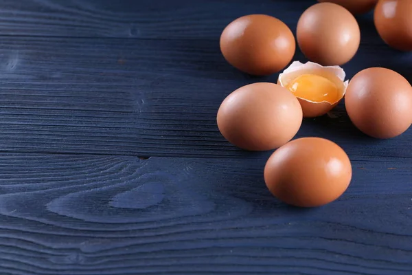 chicken eggs with one cracked egg on blue wooden background