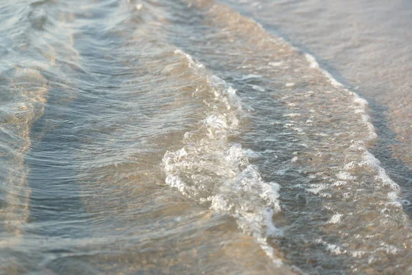 黄金の砂の背景に海の波がある澄んだ海水 — ストック写真