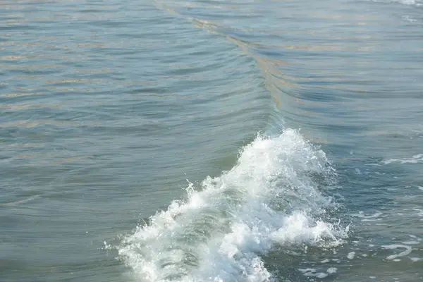 波が渦巻くターコイズブルーの海の水と海の岸の白い泡 — ストック写真