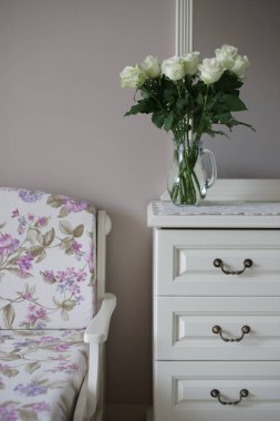 blooming colored sakura roses bouquet on dresser in bedroom background