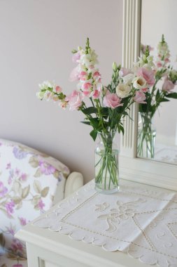 blooming colored sakura roses bouquet on dresser in bedroom background