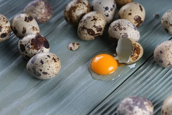 quail eggs with one cracked egg on gray wooden texture background