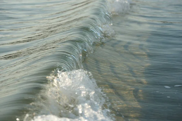 美丽的海浪在阳光明媚的海滩背景上荡漾在清澈的水面上 — 图库照片