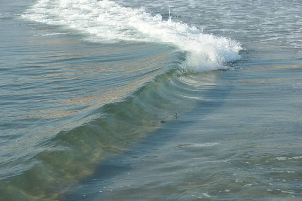 波が渦巻くターコイズブルーの海の水と海の岸の白い泡 — ストック写真