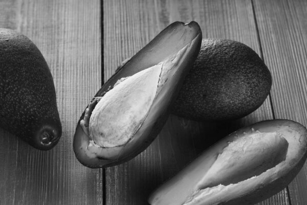 half of ripe avocado on avocados on blue wooden table background