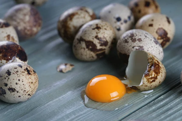 quail eggs with one cracked egg on gray wooden texture background