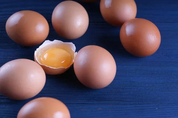 Куриные Яйца Одним Раздробленным Яйцом Синем Деревянном Фоне — стоковое фото