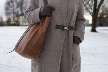 Omzunda büyük bir deri çanta olan ceketli bir kadın.