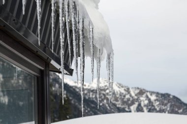 Çatının çatısından sarkan keskin buz saçakları.