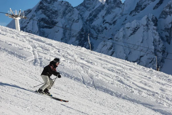 Adamın biri kayak merkezinde karlı bir yamaçta kayak yapıyor. Kayak sporu.