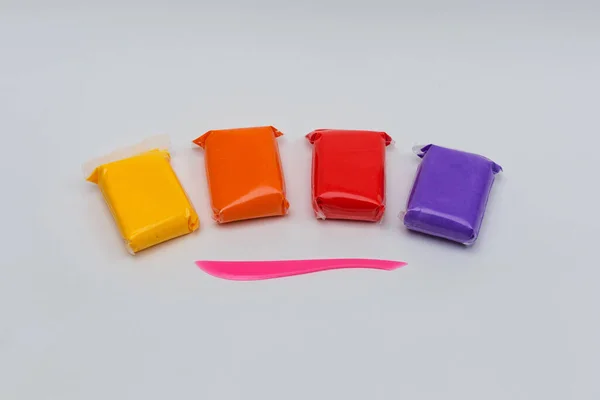 Beyaz arkaplandaki renkli plasticine paketleri.