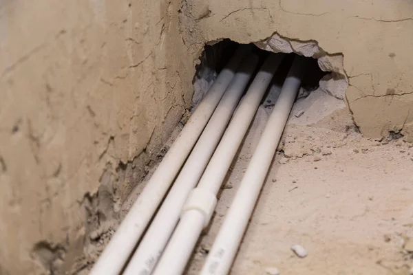 Water pipes made of polypropylene on the floor, plumbing in the house. Installation of water pipes in the bathroom of the apartment. White plastic drain pipe for water.