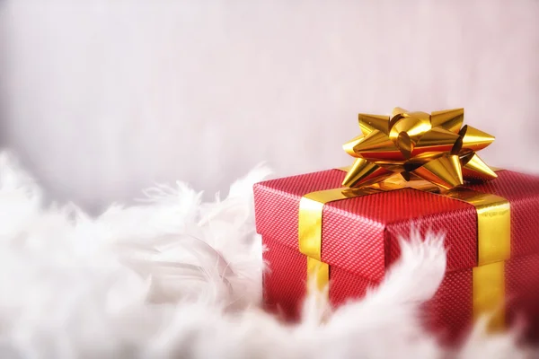 Caixa de presente vermelho com fita dourada em penas brancas frente — Fotografia de Stock