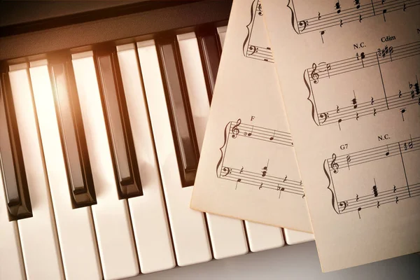 Piano keyboard with golden shine and sheet music top diagonal — Stock Photo, Image
