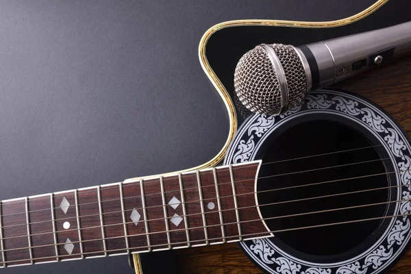 Guitare acoustique et microphone isolés sur plateau noir — Photo