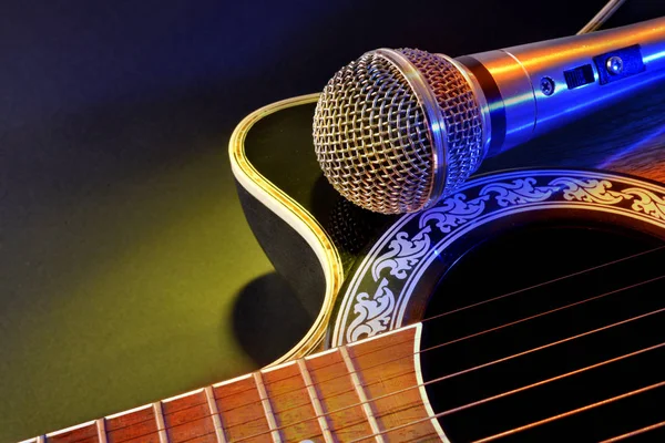 Acoustic guitar and microphone isolated with yellow and blue lig