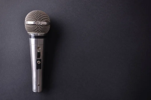 Srebrny metal mikrofon na czarny stół widok z góry — Zdjęcie stockowe