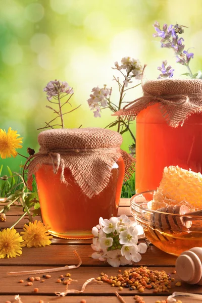 Zwei Honigtöpfe mit grünem Naturhintergrund mit vertikalen Blumen — Stockfoto