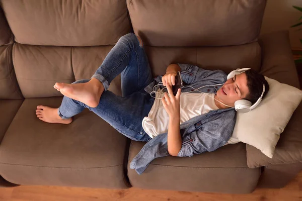 Tini fekszik felfelé kanapén fogyasztó multimédia tartalom felső — Stock Fotó