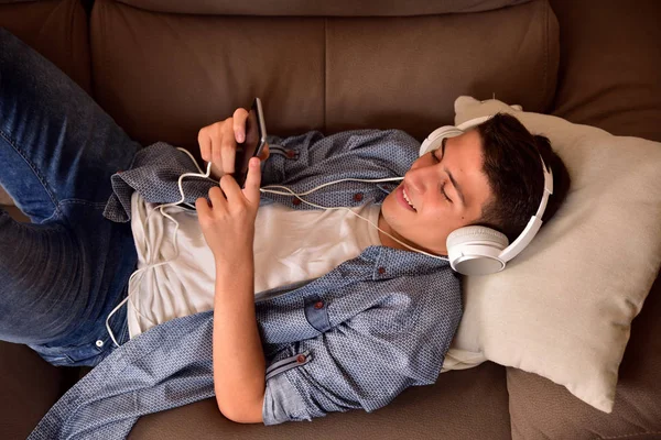 Έφηβος ξαπλωμένο πάνω στον καναπέ που καταναλώνουν multimedia κάτοψη — Φωτογραφία Αρχείου