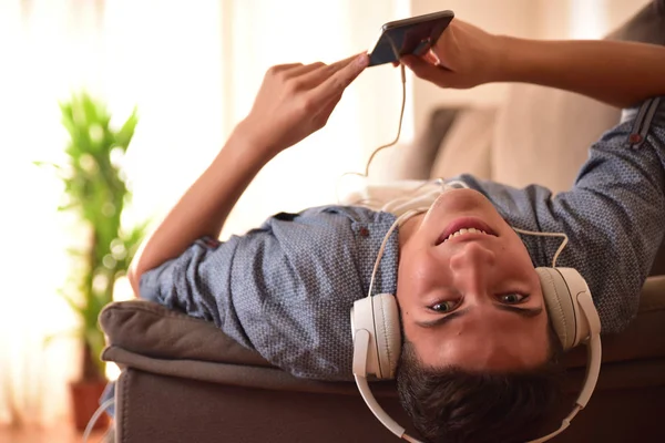 Teenager liggende ansigt op liggende på sofaen lytter musik closeup - Stock-foto